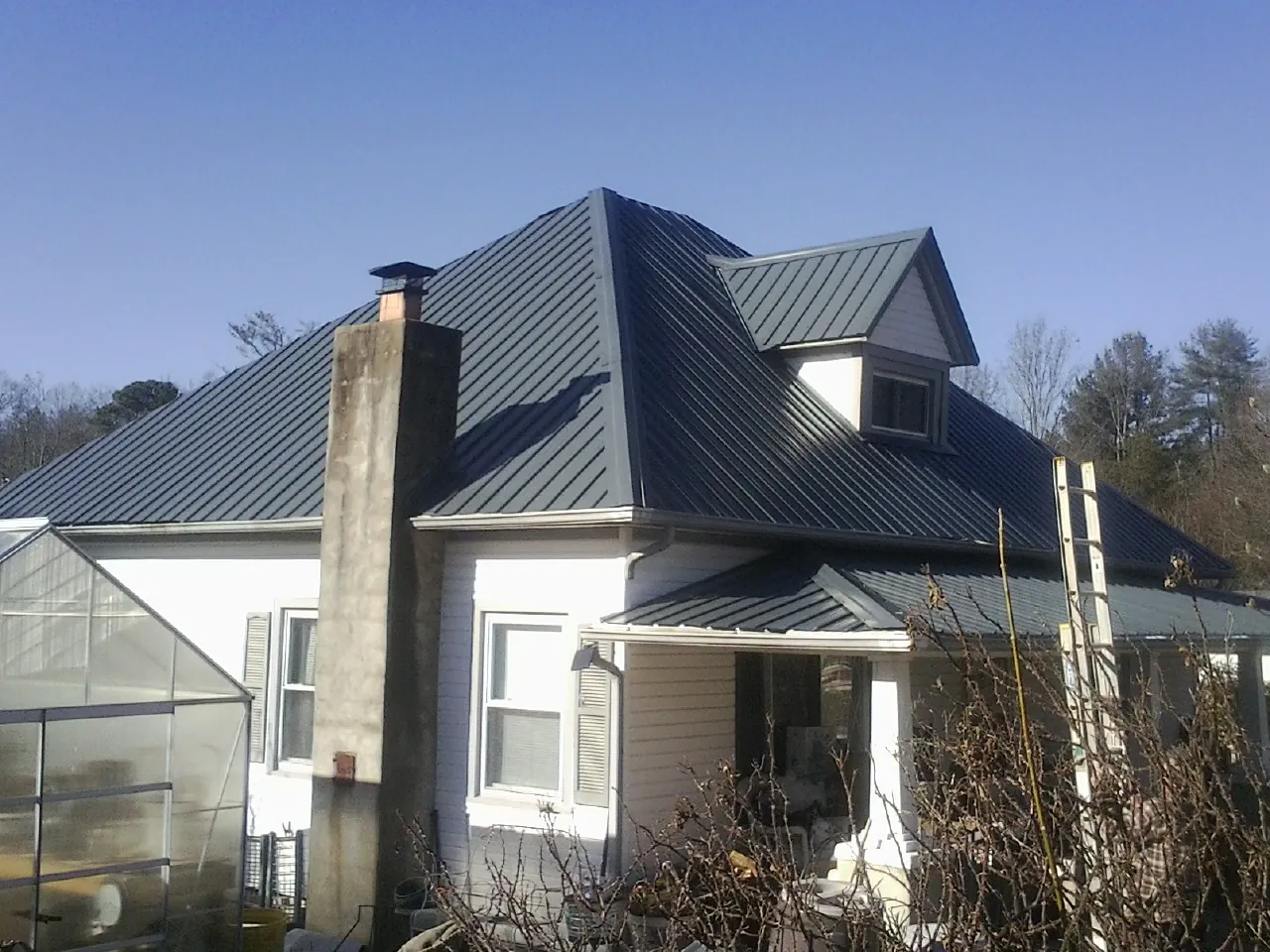 Dark blue standing seam metal roof on a white farmhouse with dormer — Slate & Tile Roof Repair by Roofing Brothers in Gladwyne