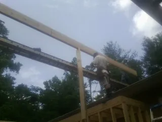 Carpenter setting a ridge beam over a new addition frame — Ice Dam Removal by Roofing Brothers in Gladwyne