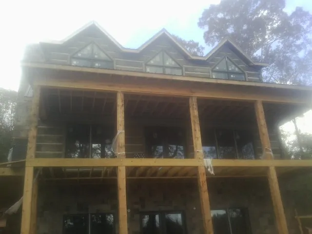 Dormers and porch framing on a large log home under construction — Roof Coating work by our crew in Gladwyne
