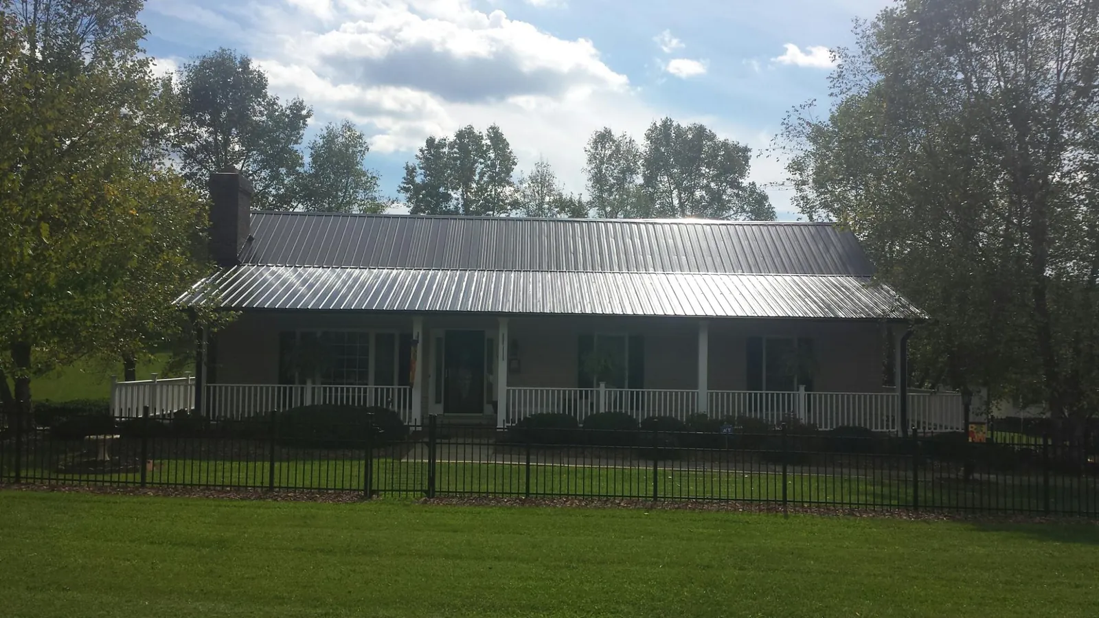 Gray metal roof on a brick ranch with a full width front porch — Gutter Guard Installation work by our crew in Gladwyne