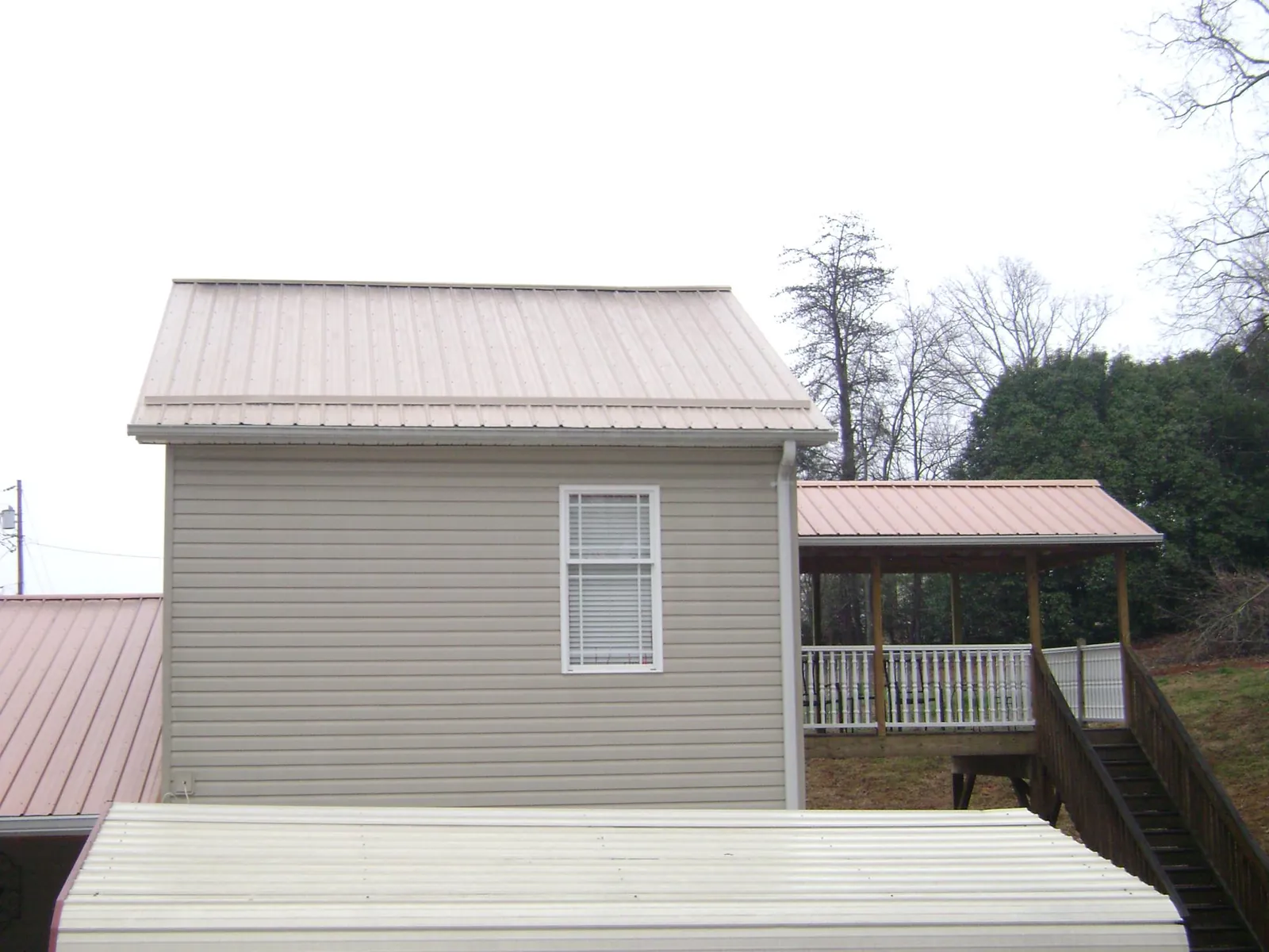 Tan metal roofs on a two story addition and attached porch, from a Roof Replacement job in Gladwyne