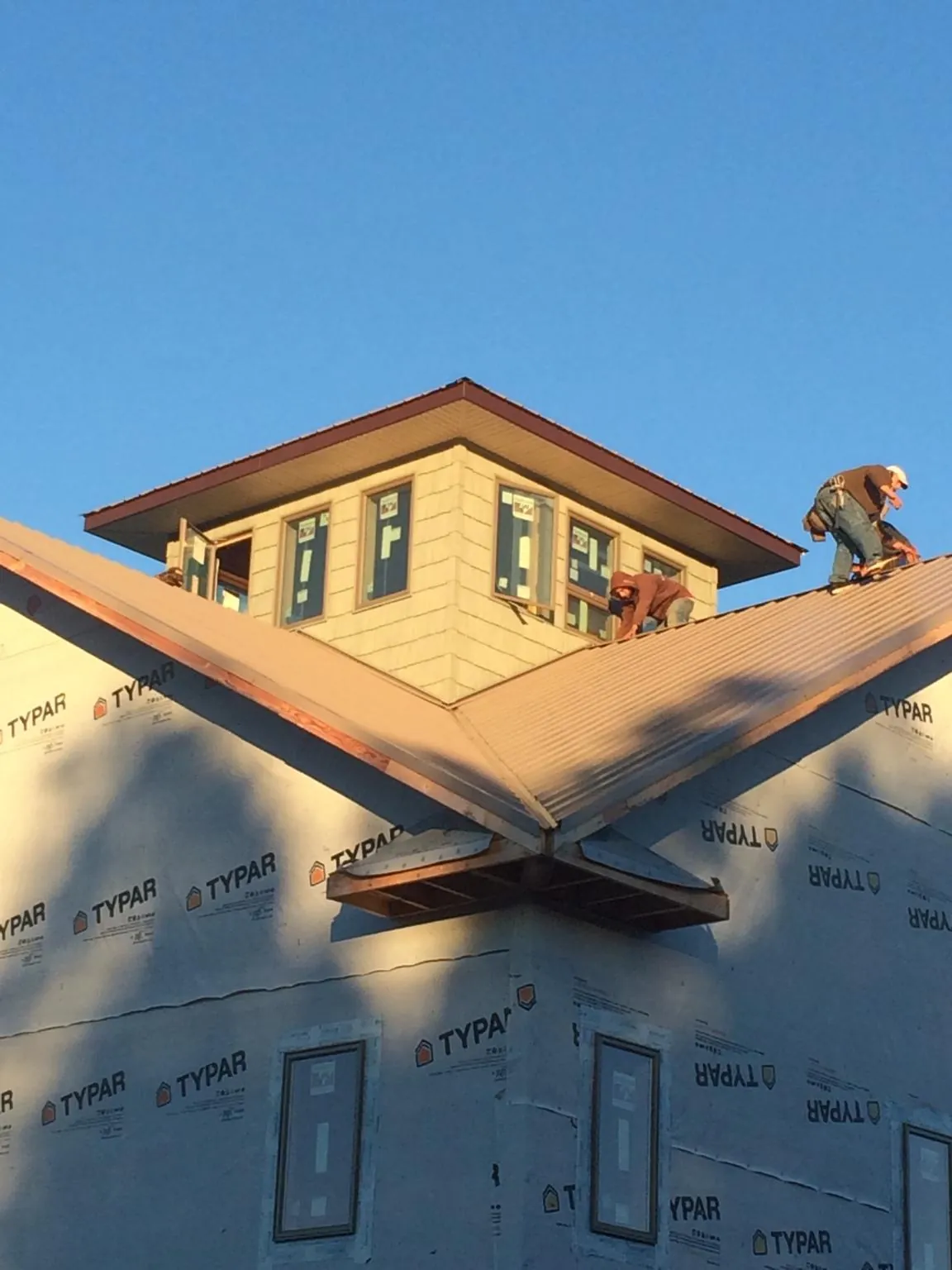 Roofers working around a rooftop cupola on a new metal roof at sunset — Roof Waterproofing in Gladwyne by Roofing Brothers